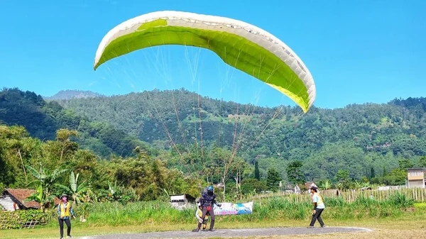 2023年7月8日にインドネシア東ジャワ州バトゥ市の緑のフィールドにパラグライダーパイロット着陸 — ストック写真