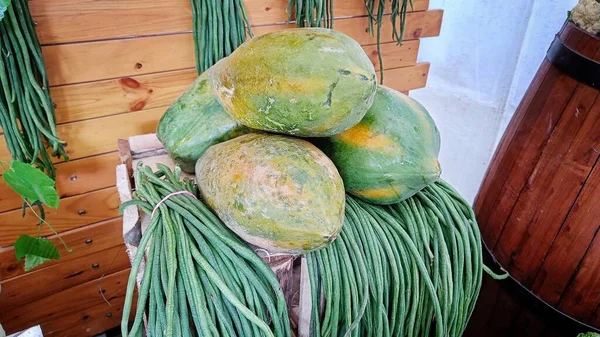 Papaya fruit and green long beans on wooden table in vegetable stall