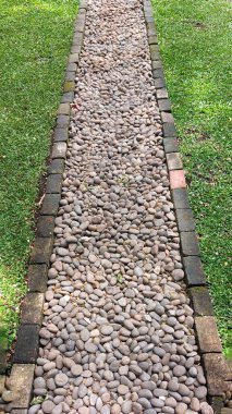 Yeşil çimenli bir bahçenin ortasındaki taş yolun simetrik bakış açısı