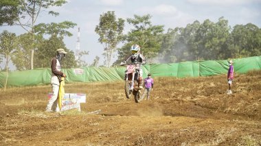 Batu City, Doğu Java, Endonezya - 31 Ağustos 2024: Motokros sürücüleri tozlu toprak yolda atlama cazibesi