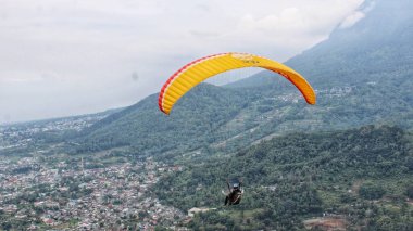 Mavi gökyüzünde ve dağ manzarasında uçan paraglider