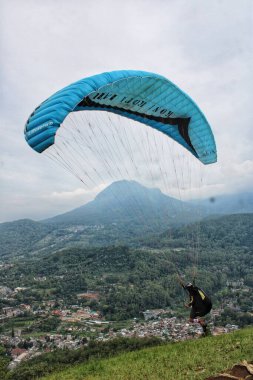 Paraglider pilotu bir tepeden havalandıktan sonra uçuyor