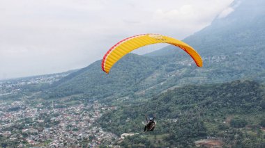 Paraglider köy manzarası ve mavi gökyüzü arkaplanı üzerinde uçuyor