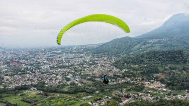 Paraglider köy manzarası ve mavi gökyüzü arkaplanı üzerinde uçuyor