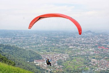 Paraglider köy manzarası ve mavi gökyüzü arkaplanı üzerinde uçuyor