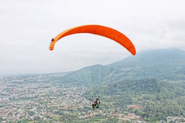 Paraglider köy manzarası ve mavi gökyüzü arkaplanı üzerinde uçuyor