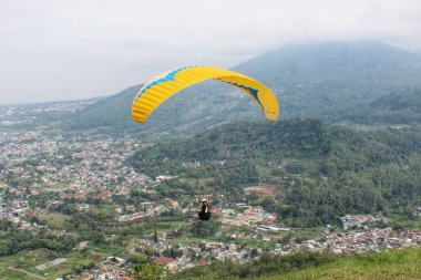Paraglider köy manzarası ve mavi gökyüzü arkaplanı üzerinde uçuyor