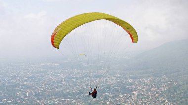 Paraglider köy manzarası ve mavi gökyüzü arkaplanı üzerinde uçuyor