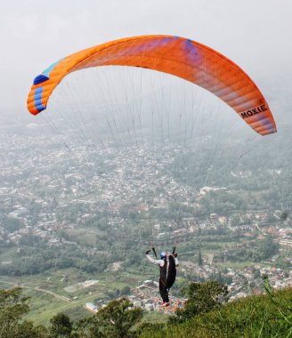 Paraglider köy manzarası ve mavi gökyüzü arkaplanı üzerinde uçuyor