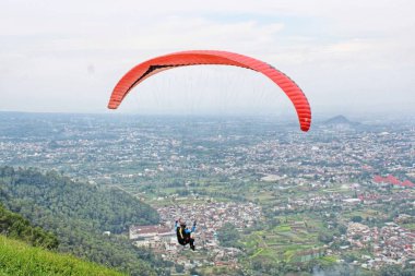 Paraglider köy manzarası ve mavi gökyüzü arkaplanı üzerinde uçuyor