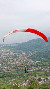 Paraglider pilotu mavi gökyüzünde uçuyor köy ve dağ manzaralı