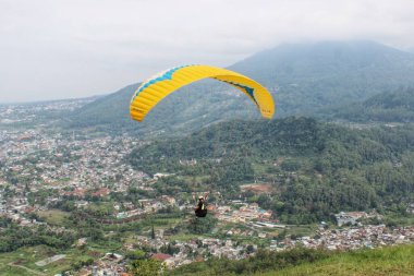 Paraglider pilotu mavi gökyüzünde uçuyor köy ve dağ manzaralı