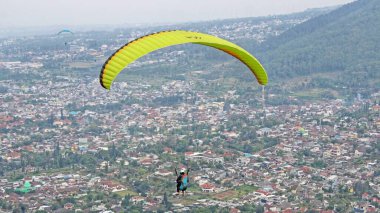 Paraglider köy manzarası ve mavi gökyüzü arkaplanı üzerinde uçuyor