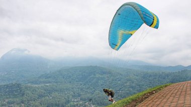 Paraglider pilotu bir tepeden havalandıktan sonra uçuyor