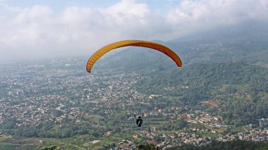 Paraglider köy manzarası ve mavi gökyüzü arkaplanı üzerinde uçuyor