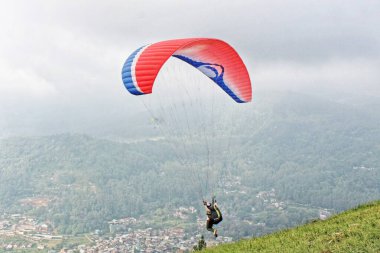 Paraglider köy manzarası ve mavi gökyüzü arkaplanı üzerinde uçuyor