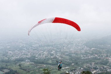 Paraglider köy manzarası ve mavi gökyüzü arkaplanı üzerinde uçuyor