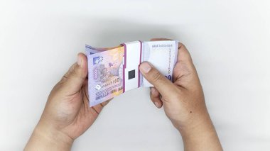 10,000 rupilik banknotta Endonezya banknotlarını sayan iki el.
