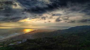 Kumsalla yeşil orman arasında gün batımının havadan manzarası