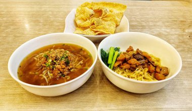 Lezzetli iki kase tavuklu sarı erişte ve beyaz tabakta servis edilen kızarmış tavuk.