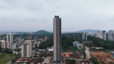 Konut evleri, ticari binalar ve uzak tepelerle dolu canlı bir şehir caddesinin insansız hava aracı görüntüsü