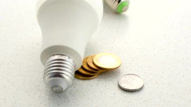 Lambanın altındaki Brezilya sikkeleri, elektrik faturası üzerindeki mali etkisini, aydınlatmanın ekonomik görünümünü temsil ediyor..