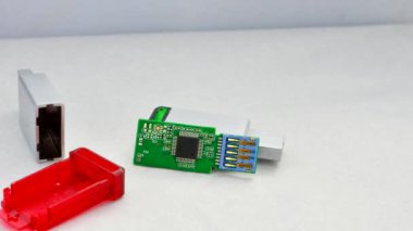Parçalanmış USB flaş bellek odaklı, bileşenlerini açık bir zeminde gösteriyor. Parçalanmış bir USB flaş belleğin beyaz desenli bir yüzeyde detaylı görünümü, yapısını gösterir.