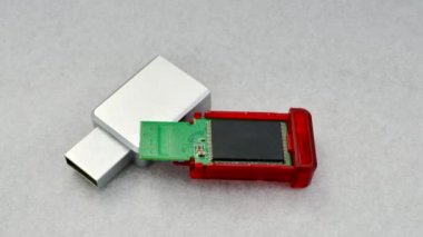 Parçalanmış USB flaş bellek odaklı, bileşenlerini açık bir zeminde gösteriyor. Parçalanmış bir USB flaş belleğin beyaz desenli bir yüzeyde detaylı görünümü, yapısını gösterir.