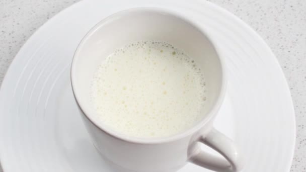 精美的牛奶杯放在白桌上 营造出宁静迷人的氛围 舒适的牛奶杯集中在一张白色的桌子上 促进平静和安宁 — 图库视频影像