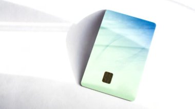 Beyaz bir yüzeyde kredi kartı, tarafsız bir finansal bağlamda zarafet ve pratik. İşlemlerde basitlik ve çok yönlülüğü vurgulayan beyaz bir yüzeyde kredi kartı.