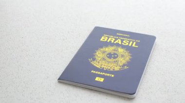 Beyaz bir yüzeyde Brezilya pasaportu, basit ve zarif bir şekilde ulusal kimliği temsil ediyor..