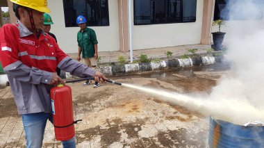 Banjarmasin, Endonezya. 6 Kasım 2021 'de erkekler yangın söndürücüyü kullanarak bir yangın söndürücüyü canlandırdı.