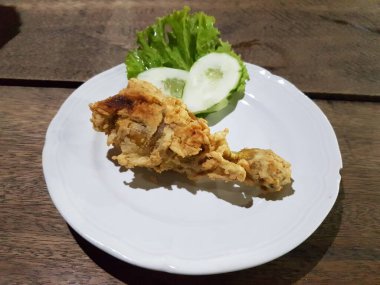 Crispy fried chicken with lettuce and cucumber on white plate