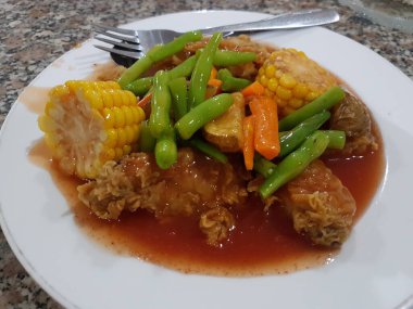 Fried chicken with sweet and sour sauce on white plate, Thailand.