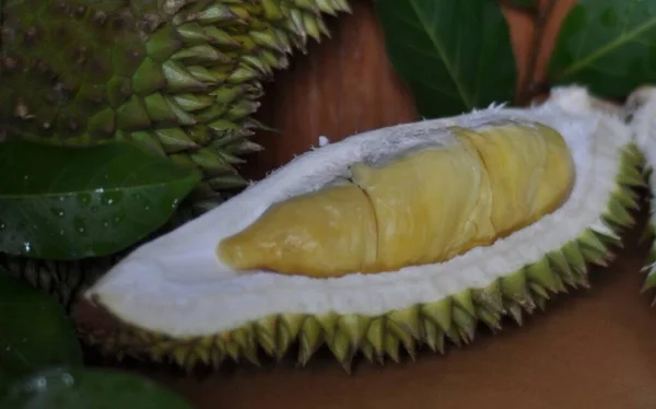 Whole and sliced durians with fruit served on wooden table