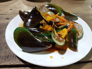 Lezzetli, tatlı ve ekşi baharatlı deniz ürünleri. Beyaz tavada haşlanmış midye. Bitkiler, tereyağı, kireç, maydanoz ve sarımsak..