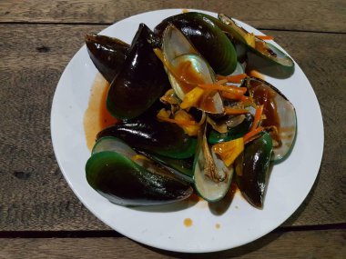 Lezzetli, tatlı ve ekşi baharatlı deniz ürünleri. Beyaz tavada haşlanmış midye. Bitkiler, tereyağı, kireç, maydanoz ve sarımsak..