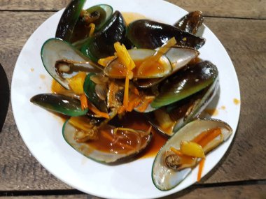 Lezzetli, tatlı ve ekşi baharatlı deniz ürünleri. Beyaz tavada haşlanmış midye. Bitkiler, tereyağı, kireç, maydanoz ve sarımsak..