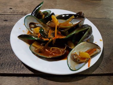 Lezzetli, tatlı ve ekşi baharatlı deniz ürünleri. Beyaz tavada haşlanmış midye. Bitkiler, tereyağı, kireç, maydanoz ve sarımsak..