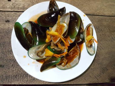 Lezzetli, tatlı ve ekşi baharatlı deniz ürünleri. Beyaz tavada haşlanmış midye. Bitkiler, tereyağı, kireç, maydanoz ve sarımsak..