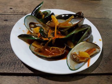 Lezzetli, tatlı ve ekşi baharatlı deniz ürünleri. Beyaz tavada haşlanmış midye. Bitkiler, tereyağı, kireç, maydanoz ve sarımsak..