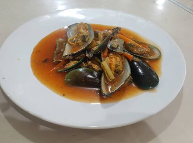 Lezzetli, tatlı ve ekşi baharatlı deniz ürünleri. Beyaz tavada haşlanmış midye. Bitkiler, tereyağı, kireç, maydanoz ve sarımsak..