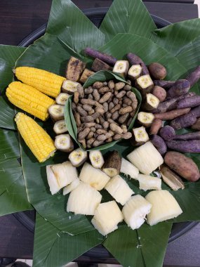 Muz, kasava, tatlı patates, fıstık, haşlanmış mısır gibi lezzetli geleneksel Endonezya yemekleri örülmüş bambu tepside muz yaprağı pedleri ile servis edilir.