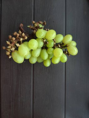 Siyah sehpada bir demet yeşil üzüm ve yazı için yeri olan ahşap arkaplan.