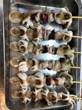 Açık hava yiyecek pazarında servis edilen bambu çubuğuyla ızgara yapılmış lezzetli kalamar ve ahtapot. egzotik Asya yemekleri. 