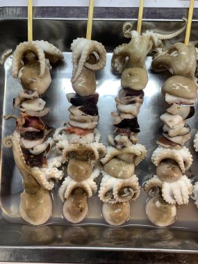 Açık hava yiyecek pazarında servis edilen bambu çubuğuyla ızgara yapılmış lezzetli kalamar ve ahtapot. egzotik Asya yemekleri. 