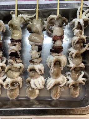 Açık hava yiyecek pazarında servis edilen bambu çubuğuyla ızgara yapılmış lezzetli kalamar ve ahtapot. egzotik Asya yemekleri. 