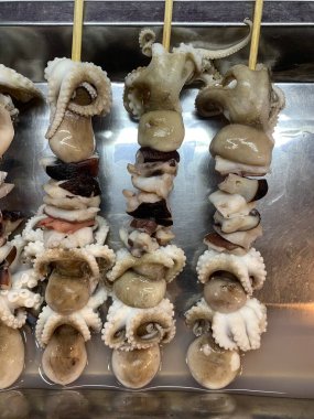 Açık hava yiyecek pazarında servis edilen bambu çubuğuyla ızgara yapılmış lezzetli kalamar ve ahtapot. egzotik Asya yemekleri. 