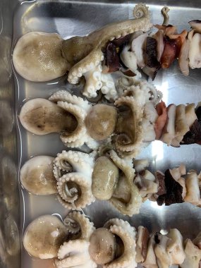 Açık hava yiyecek pazarında servis edilen bambu çubuğuyla ızgara yapılmış lezzetli kalamar ve ahtapot. egzotik Asya yemekleri. 