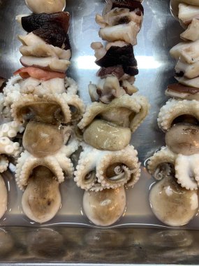 Açık hava yiyecek pazarında servis edilen bambu çubuğuyla ızgara yapılmış lezzetli kalamar ve ahtapot. egzotik Asya yemekleri. 